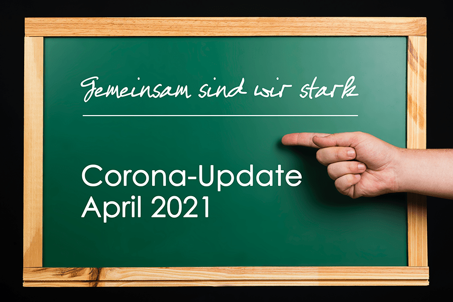 Eine grüne Kreidetafel mit einem Holzrahmen zeigt den Text Gemeinsam sind wir stark, Corona-Update April 2021, und eine rechte Hand, die auf den Text zeigt, mit einem schwarzen Hintergrund hinter der Tafel.